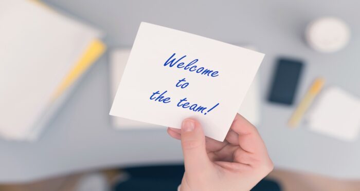 Hand holding a welcome to the team card symbolizing new employee onboarding and cybersecurity awareness – Mentis Group IT support